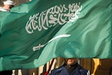 An Honour Guard member is covered by the flag of Saudi Arabia.