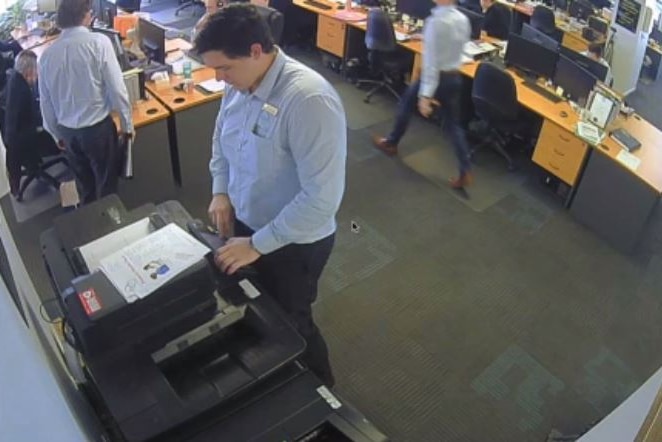 A man stands at a photocopier in a Queensland office.