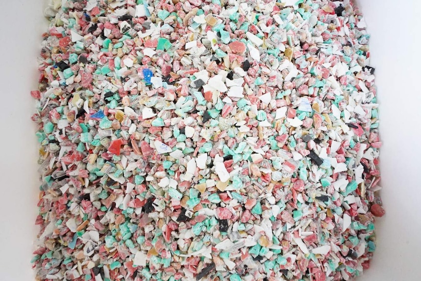 Thousands of small and colourful pieces of broken down plastic in a white bucket.