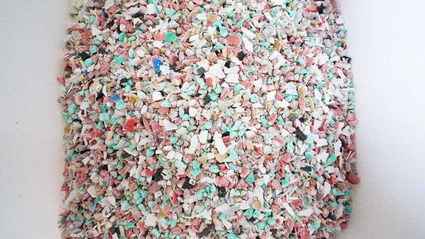Thousands of small and colourful pieces of broken down plastic in a white bucket.