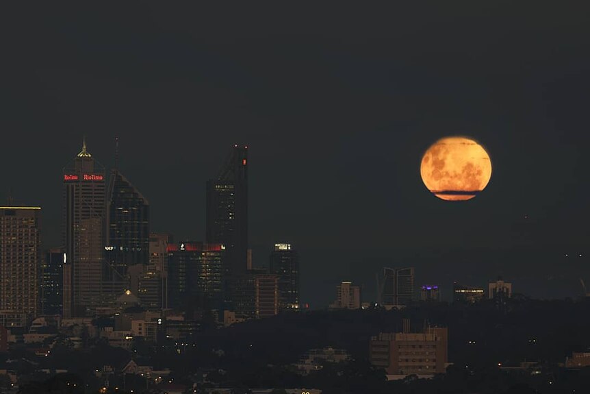 A full moon above a city at night.