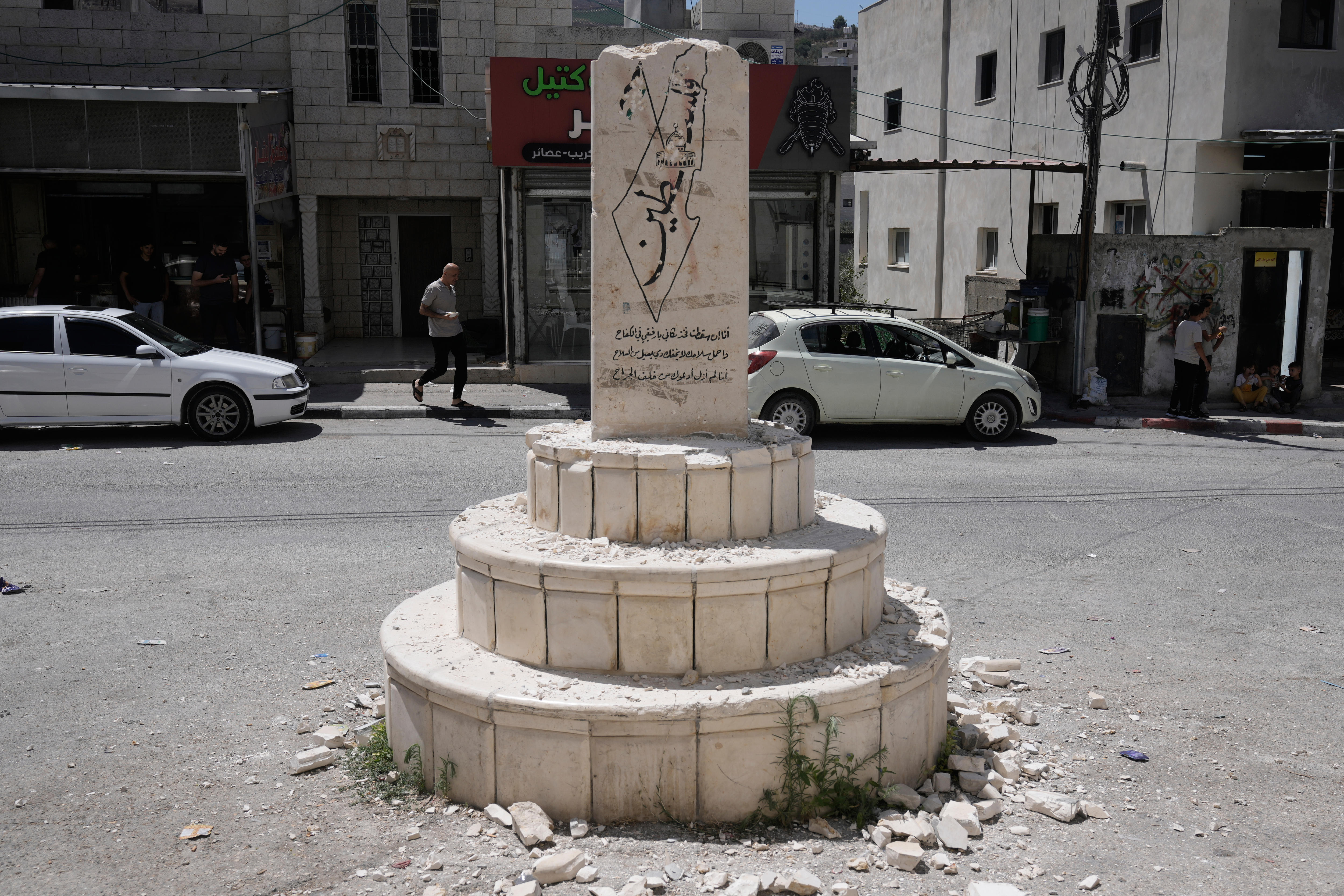 A memorial stands amid rubble on an empty street.