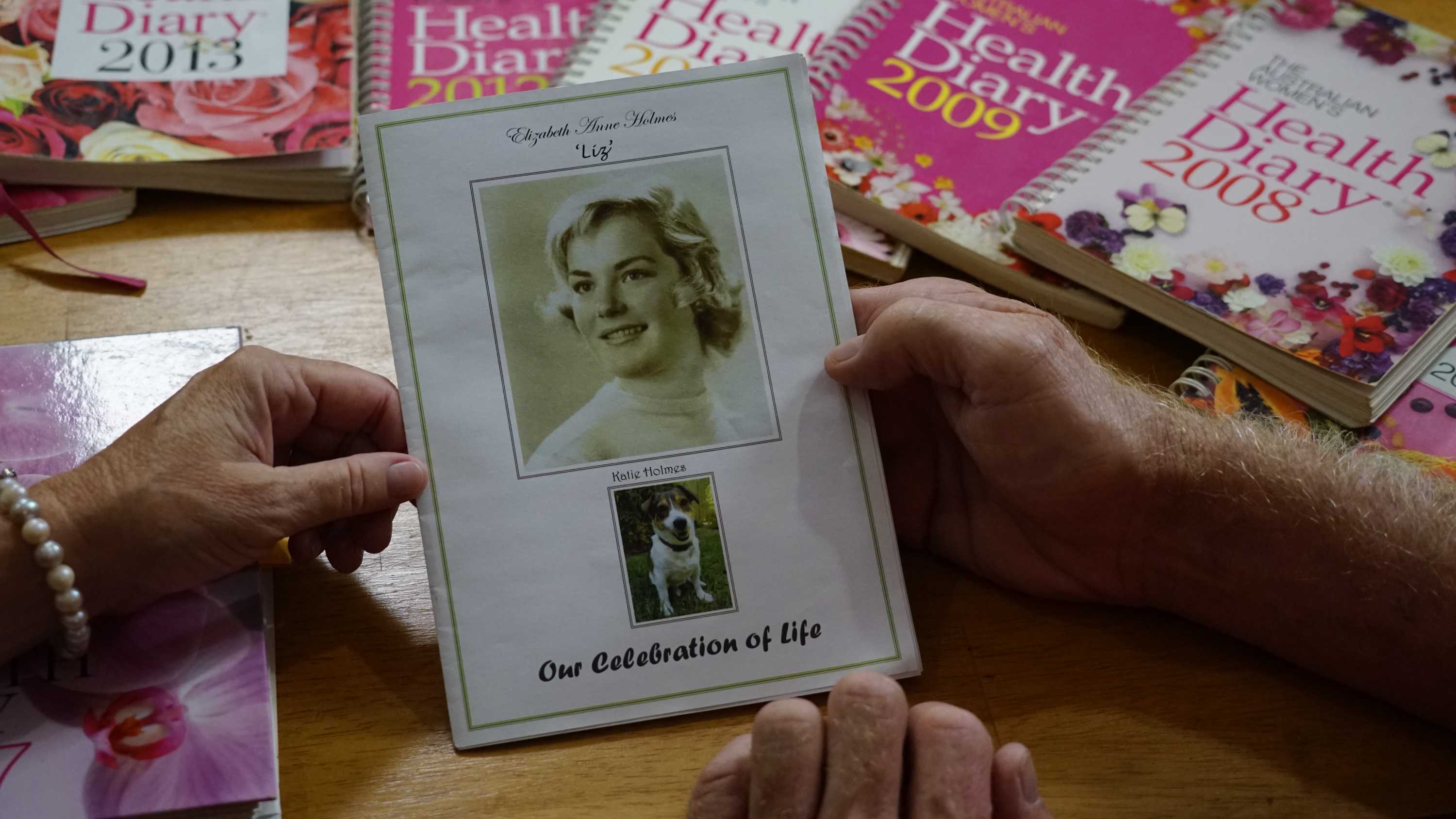 Diaries can be seen spread out. In the foreground is a 'celebration of life' booklet for Liz Holmes and her dog Katie.