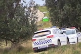 Police vehicles parked at the edges of a lake, with a small tent pitched on the shore.