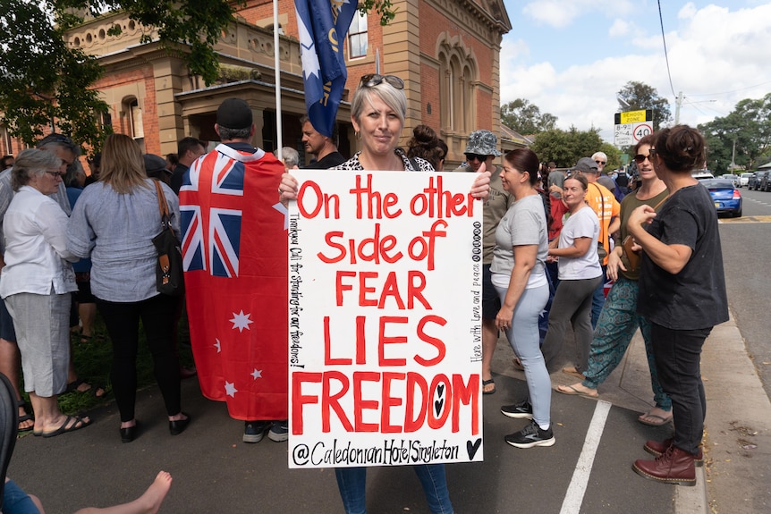 A woman holding a placard that reads "on the other side of fear lies freedom".