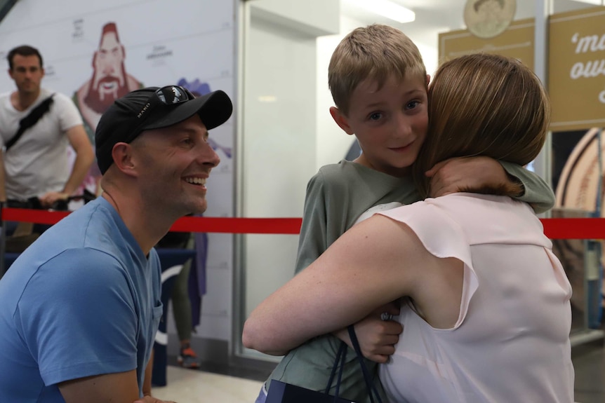 Mum Judith hugging son Henry as dad Robb looks on, smiling.