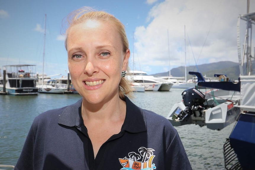 Nikki Giumelli smiles, standing in front of the water of marina.