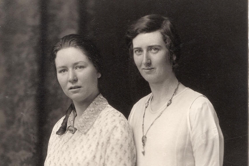 two women standing next to each other in a black and white, historical photograph