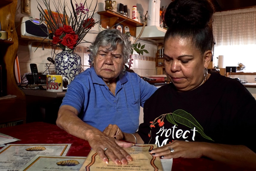 Nikki and Diana look over paperwork at the kitchen table.