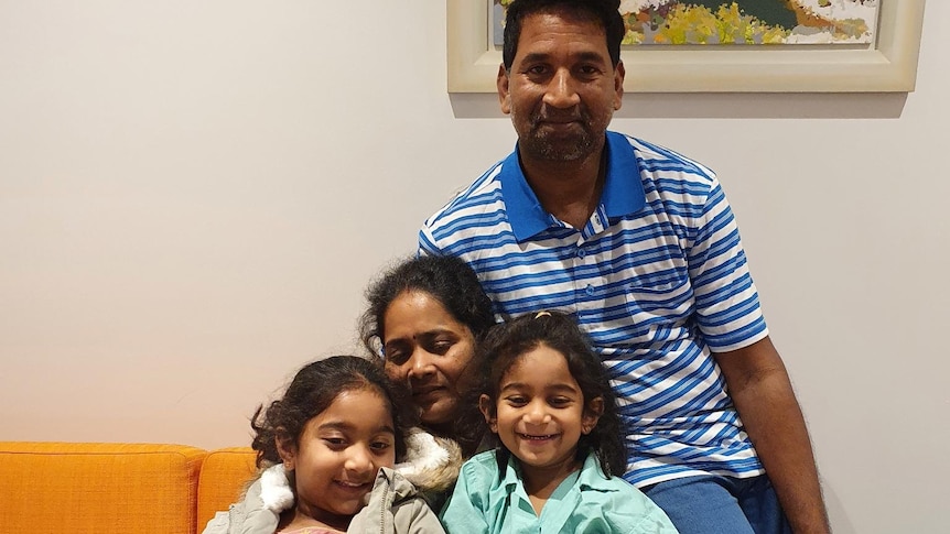 A close-up photo of the Murugappan family with a painting in the background.