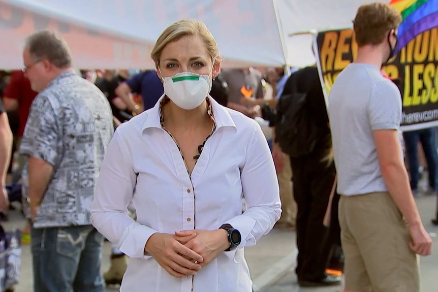 A young woman standing in a crowd in a face mask