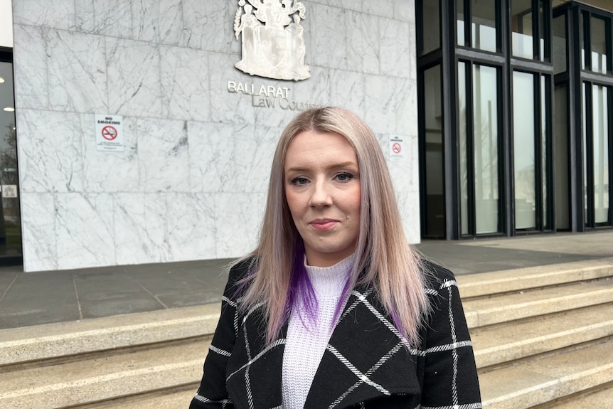 A woman with purple hair stands in front of the Ballarat law courts