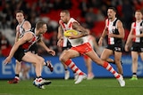 Sydney AFL star Lance Franklin runs with the ball through the St Kilda defence as players try to chase him.,