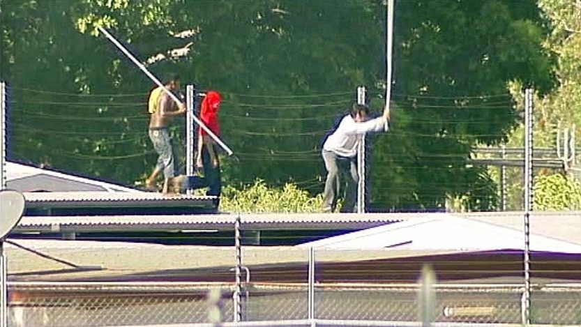 Three detainess at the Darwin immigration detention centre clamber over the roof at the centre