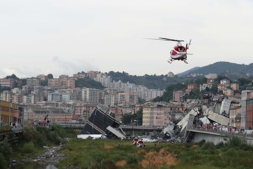 A rescue helicopter flies over the collapsed Morandi Bridge.