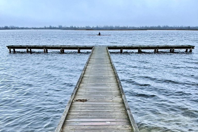A rowing boat in the distance lined up with a jetty