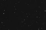 A black sky peppered with stars, and a small pink cross to indicate the black hole nearby.