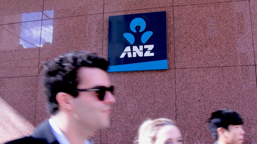 Customers walk past a ANZ logo on the wall of a bank in Sydney.
