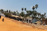 Sri Lankan soldiers (L) ride a motorcycle past a destroyed village