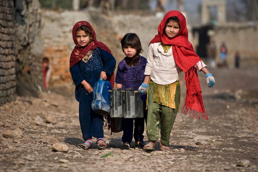 Three little Afghan girls struggle to carry containers of water