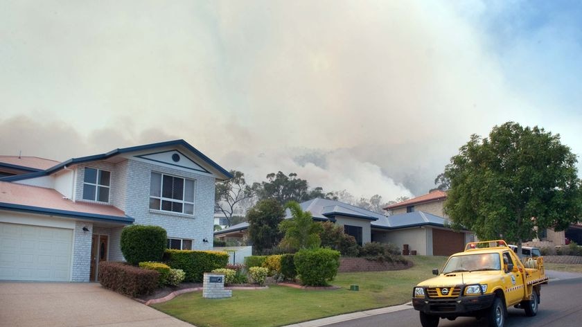 Bushfires burn behind houses at Ridgedale Avenue, at Norman Gardens in Rockhampton yesterday.