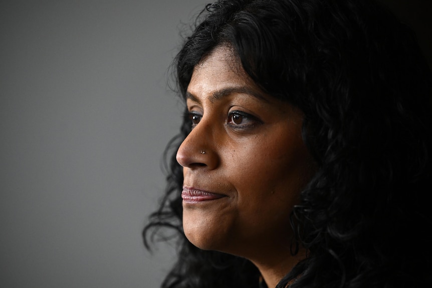 a close up photo of a woman with black hair and pursed lips. 