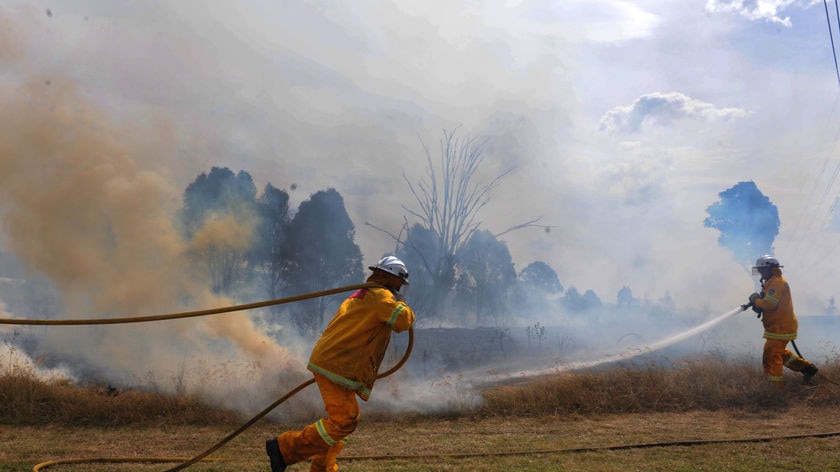 Firefighters work to contain a grass fire in NSW
