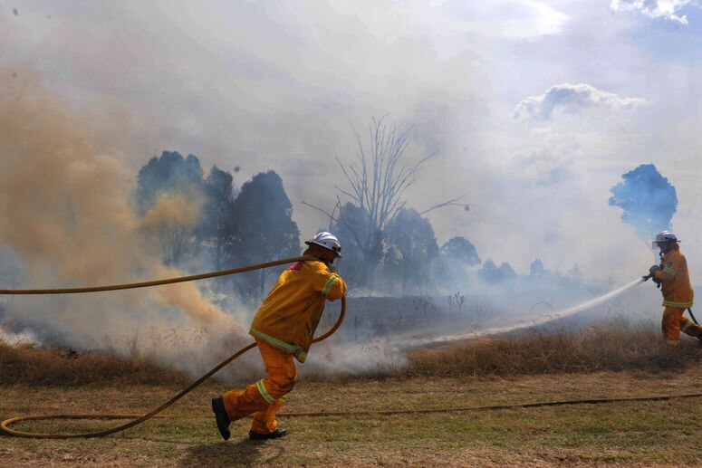 Firefighters work to contain a grass fire in NSW