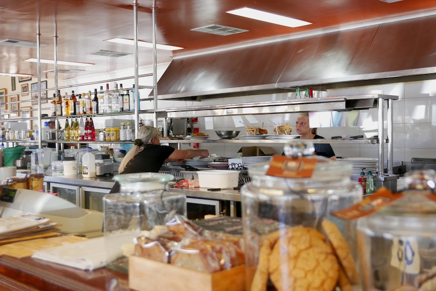 Two cafe workers talk across a counter