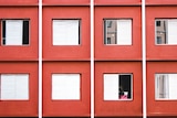 Close up view of a red apartment building and windows with white blinds. 