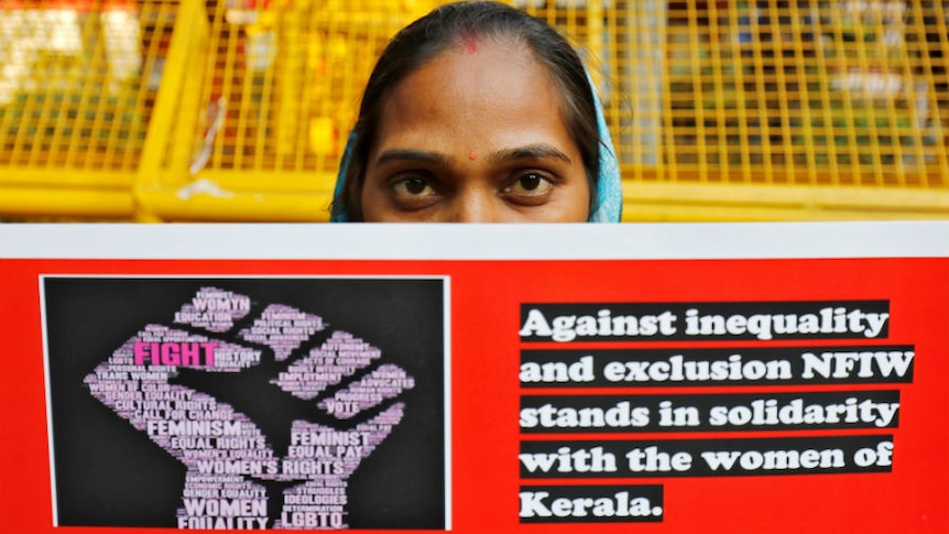 A woman holds a placard with the words "Against inequality and exclusion NFIW stands in solidarity with the women of Kerala"