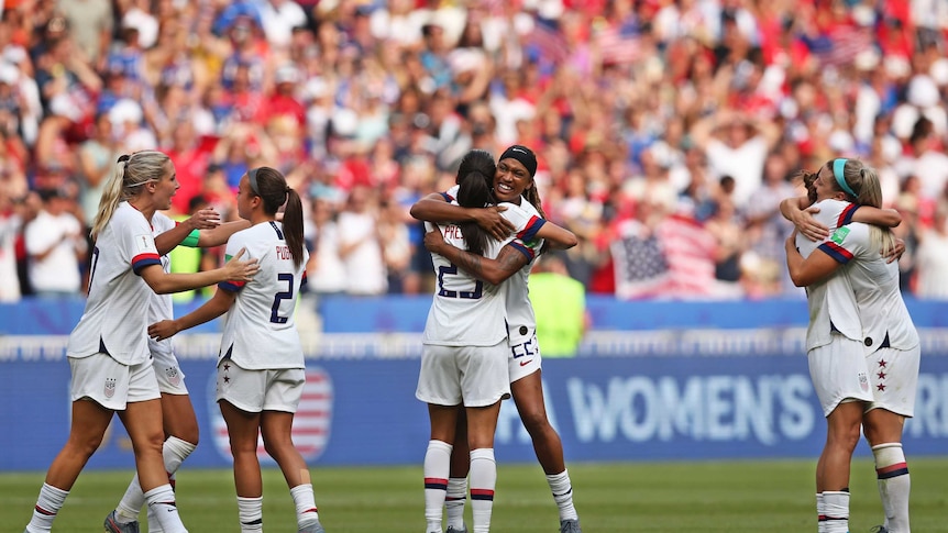 Team USA hug each other in the field following their win