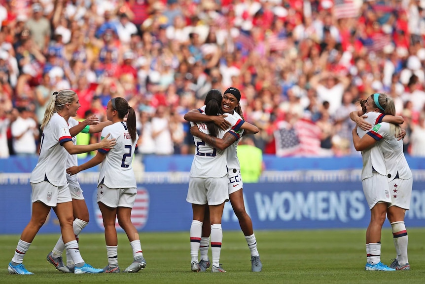 Team USA hug each other in the field following their win