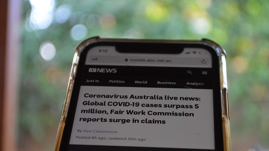 Close up of phone with Coronavirus Australia live news blog on screen.