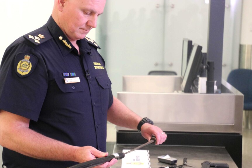 ABF Regional Commander Rod O'Donnell inspects illegal weapons brought into Australia.