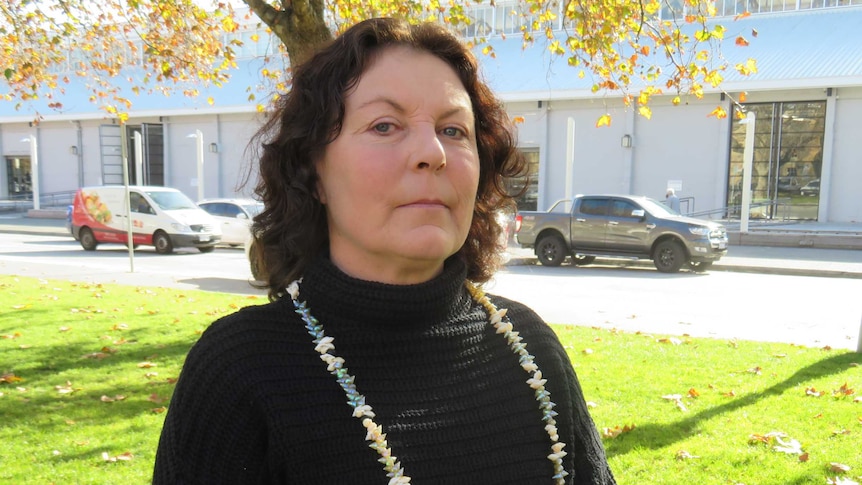 A half-body shot of Fiona Hamilton, who has her hands clasped and has a serious expression