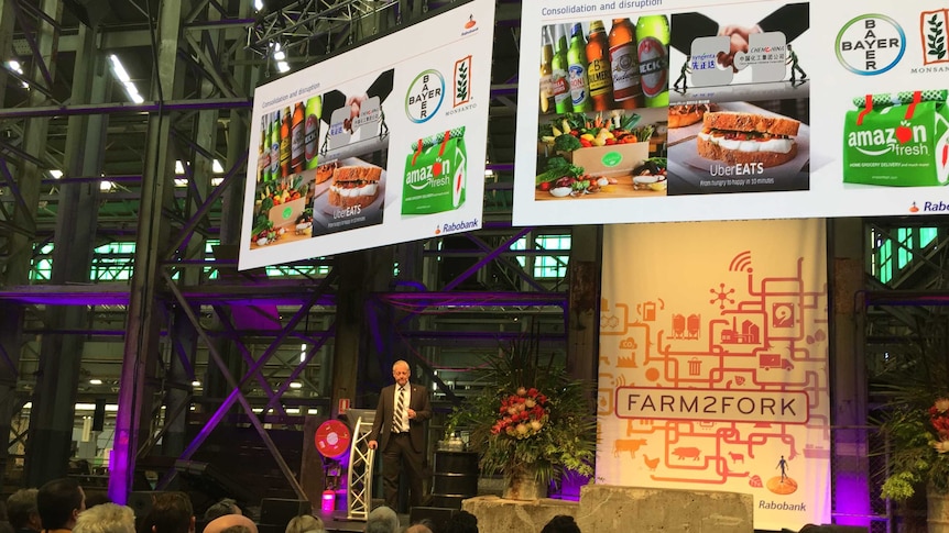 Man on stage at event with Farm2Fork banners and pictures of food and beer