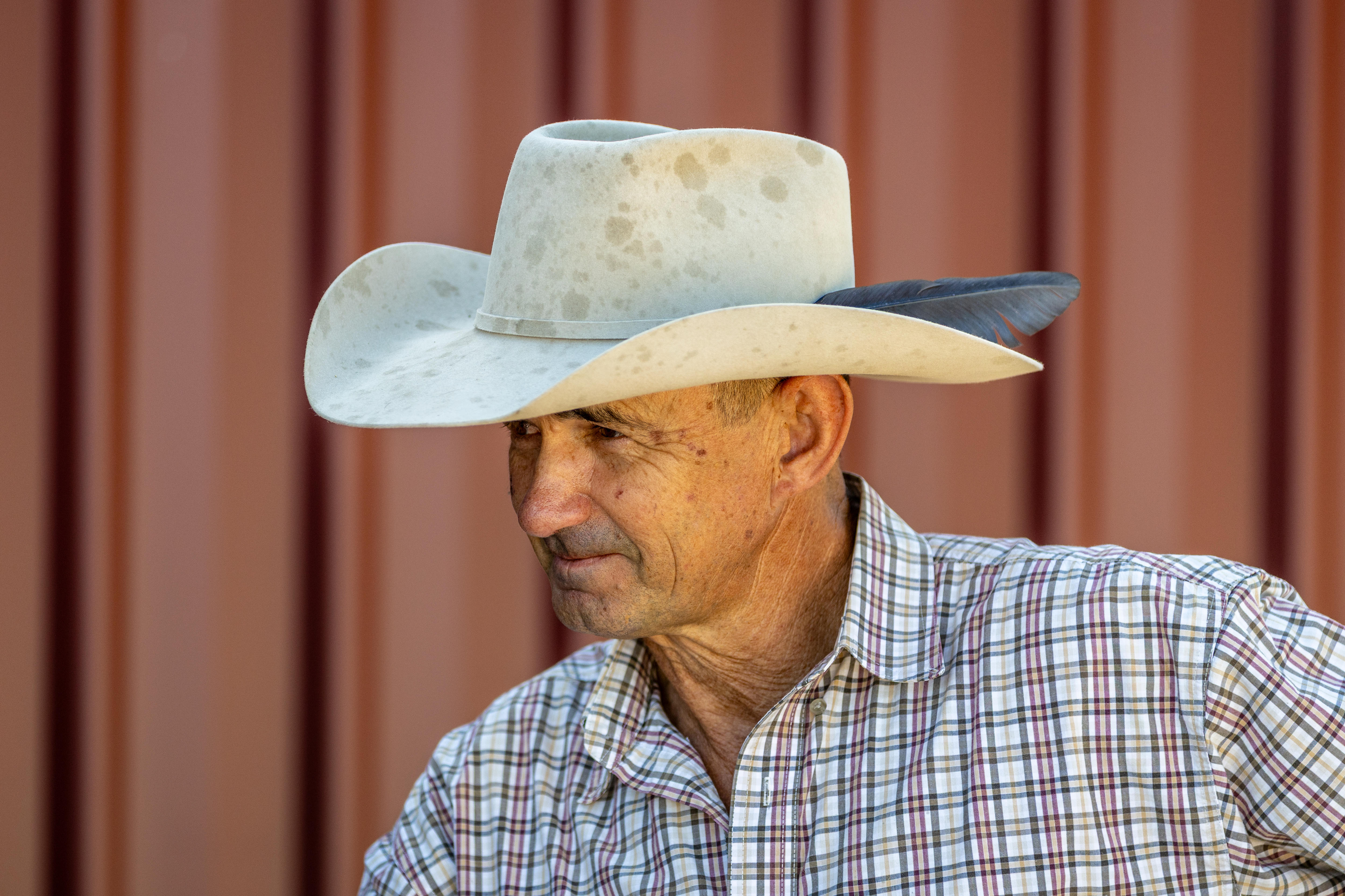 Um homem de chapéu branco e camisa xadrez.