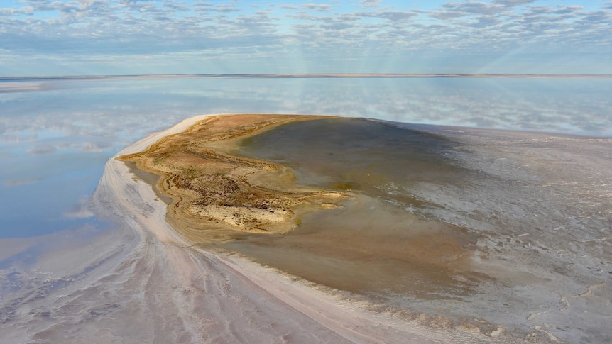 A island in the middle of water.  There is a white salt spit coming out of the side