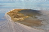 A island in the middle of water.  There is a white salt spit coming out of the side