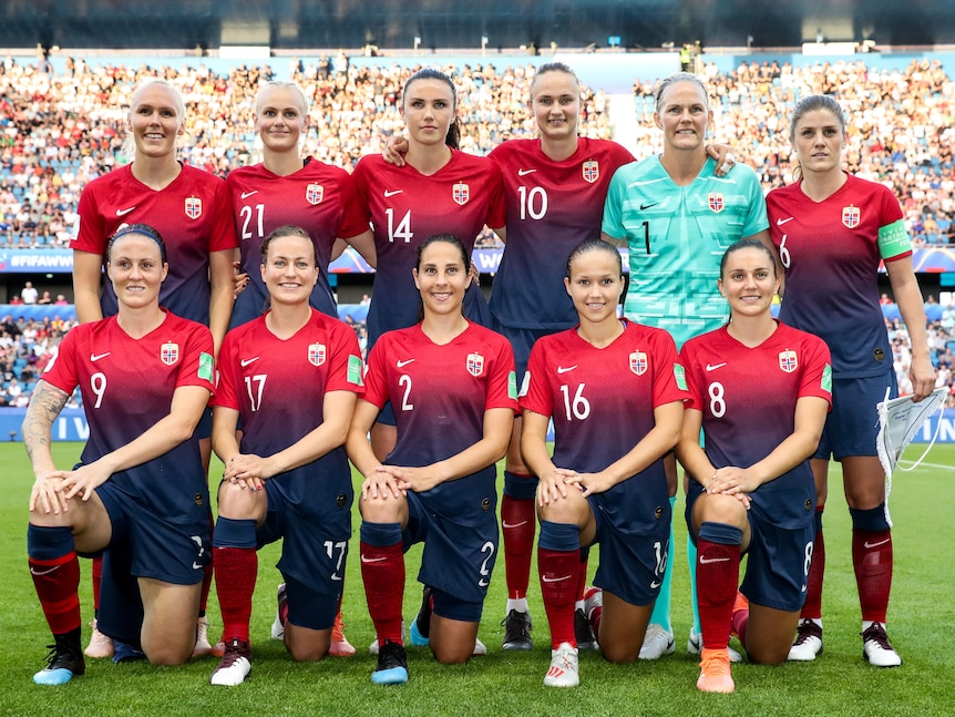 A women's soccer team wearing red and blue pose for a photo