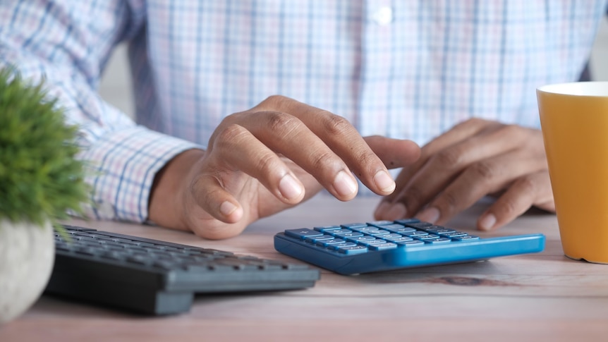 A hand resting above a calculator