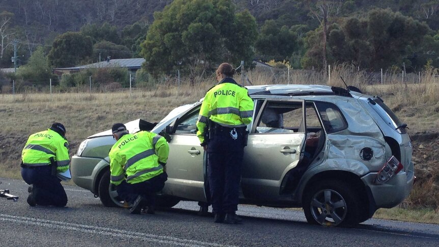 Police inspect the car involved in the fatal on the East Derwent Highway.