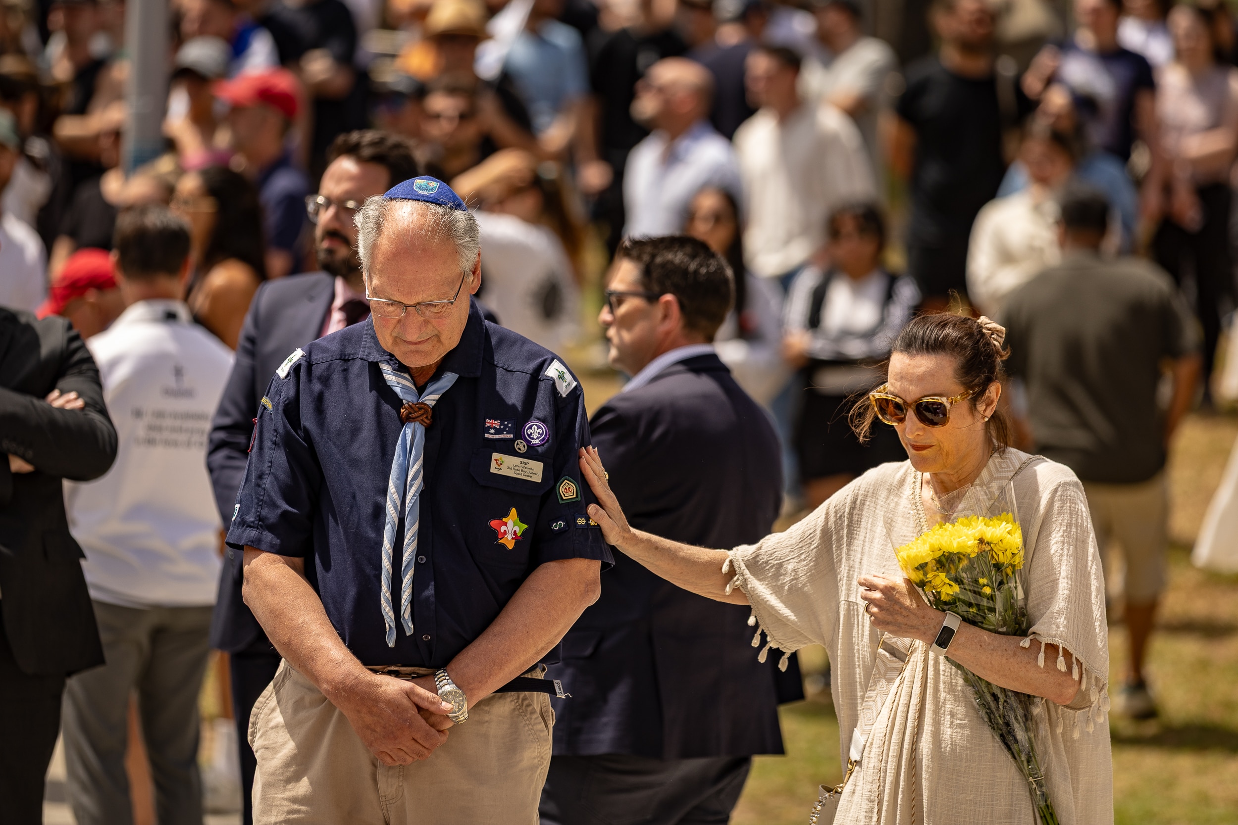 Um homem e uma mulher depositam flores e choram no memorial Bondi Pavilion