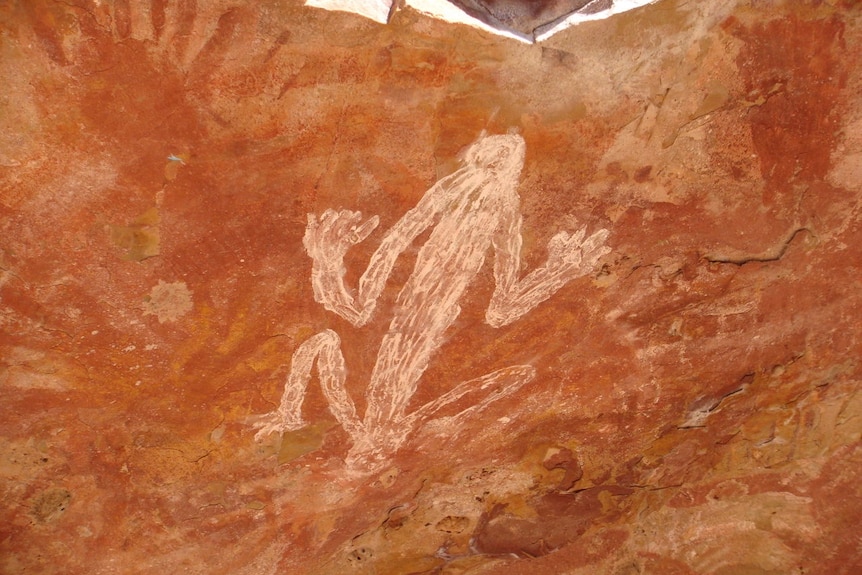 An Indigenous rock painting, featuring white ochre on a red-tinged background.