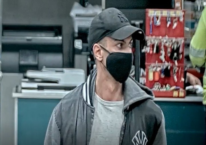 Blurry image of man in black face mask and cap in a Bunnings store