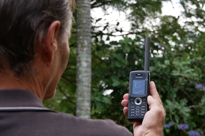 A man holds up a satellite phone