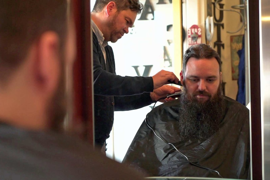 A barber trims a man's hair.