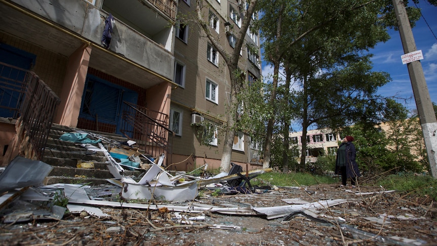 A woman looks at a building damaged by a Russian military strike in Donetsk.