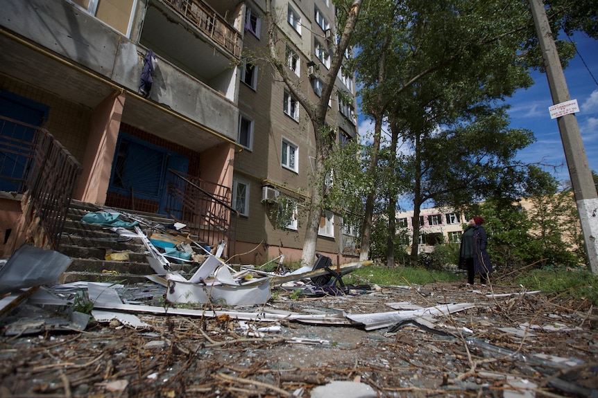 A woman looks at a building damaged by a Russian military strike in Donetsk.